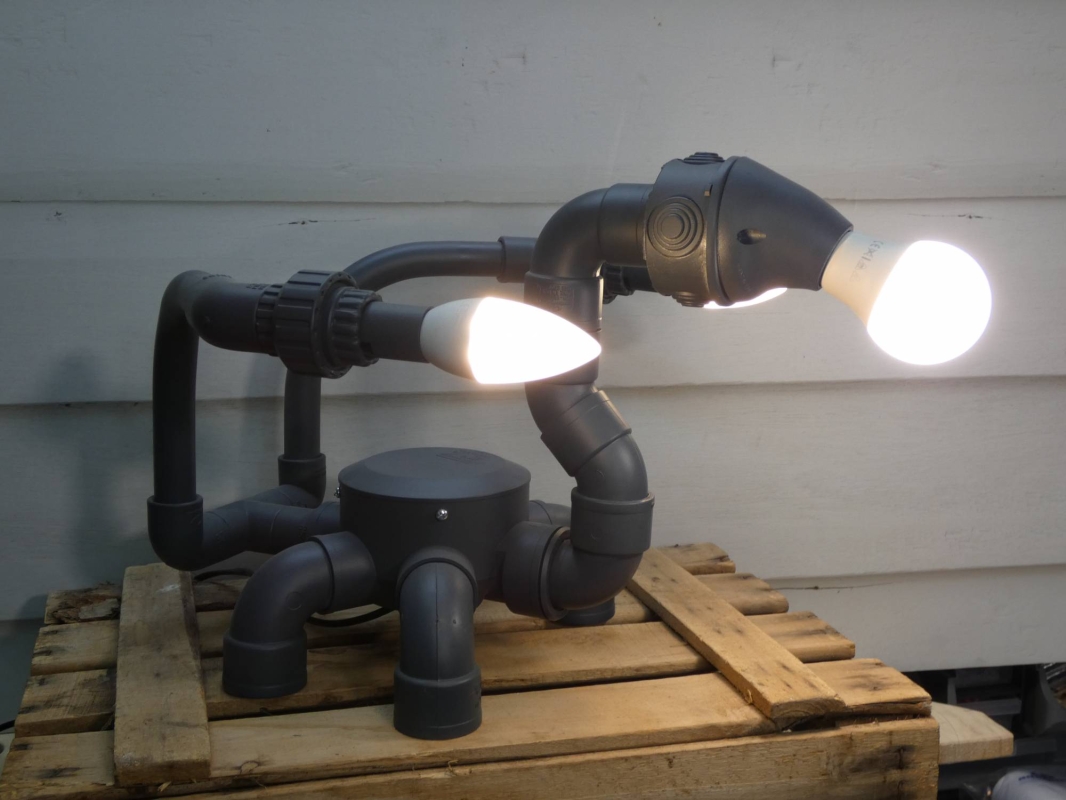 Escultura lámpara robot realizada con PVC , piezas de fontanería y electricidad , línea  robot terminator futurista efecto gris grafito. MEDIDAS: Ancho 40 cm X Alto 31 cm X Fondo 41 Bombillas incluidas