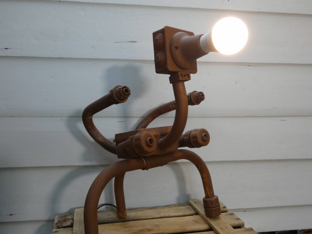 Escultura lámpara robot realizada con PVC, piezas de fontanería y electricidad, línea robot terminator  futurista efecto oxido. MEDIDAS: Ancho 40 cm X Alto 46 cm X Fondo 36 cm Bombilla incluida
