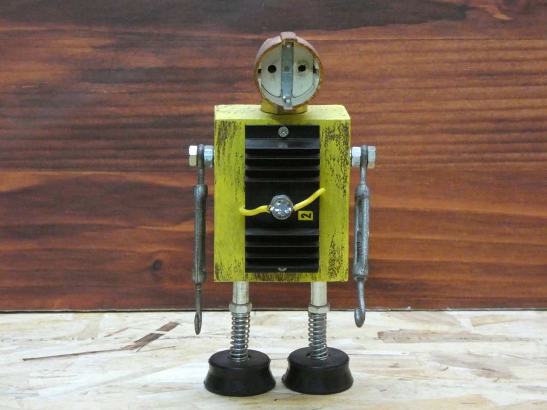 Escultura robot realizada con material reciclado, taco de madera, radiador de circuito impreso y enchufe, con pintura amarillo envejecido oxido. MEDIDAS: Ancho 25 cm X Alto 14 cm 