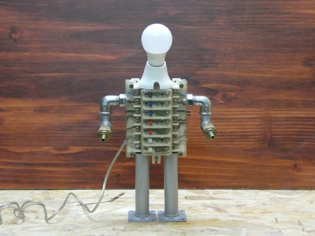 Escultura lámpara robot realizada con material reciclado, antiguo conector eléctrico y piezas de fontanería y aire comprimido. MEDIDAS: Ancho 43 cm X Alto 23 cm 