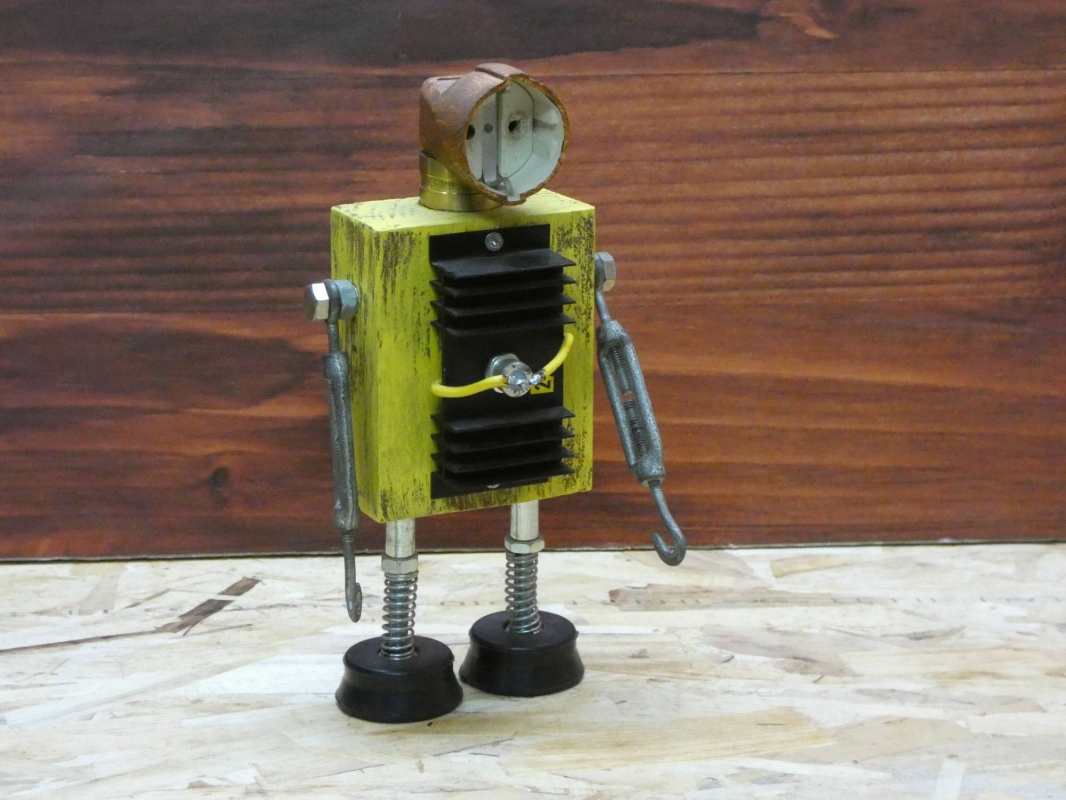 Escultura robot realizada con material reciclado, taco de madera, radiador de circuito impreso y enchufe, con pintura amarillo envejecido oxido. MEDIDAS: Ancho 25 cm X Alto 14 cm 