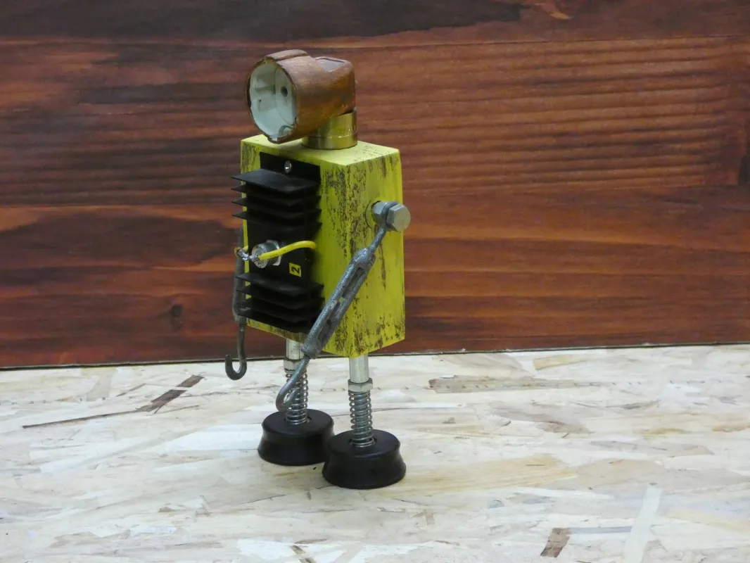 Escultura robot realizada con material reciclado, taco de madera, radiador de circuito impreso y enchufe, con pintura amarillo envejecido oxido. MEDIDAS: Ancho 25 cm X Alto 14 cm 