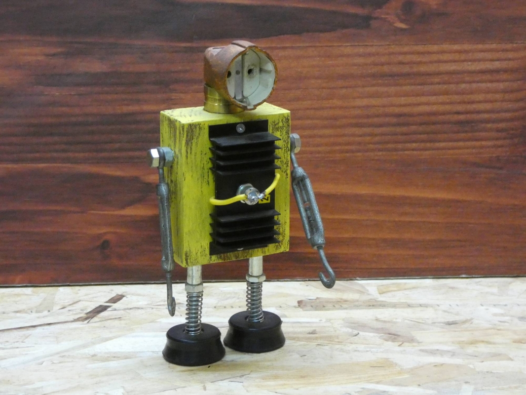 Escultura robot realizada con material reciclado, taco de madera, radiador de circuito impreso y enchufe, con pintura amarillo envejecido oxido. MEDIDAS: Ancho 25 cm X Alto 14 cm 